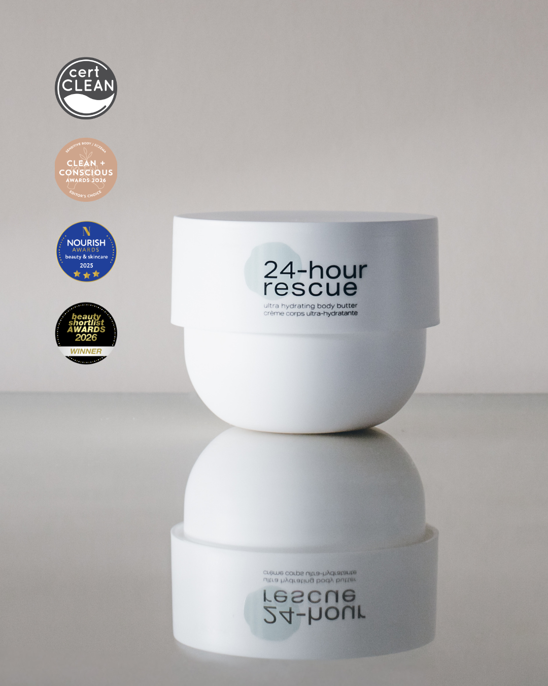 A white jar of 24-hour Rescue skin care product on a reflective light gray surface, with certification badges aligned vertically on the left.