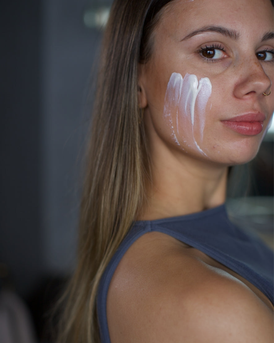 Woman with white cream on her face against a blurred background
