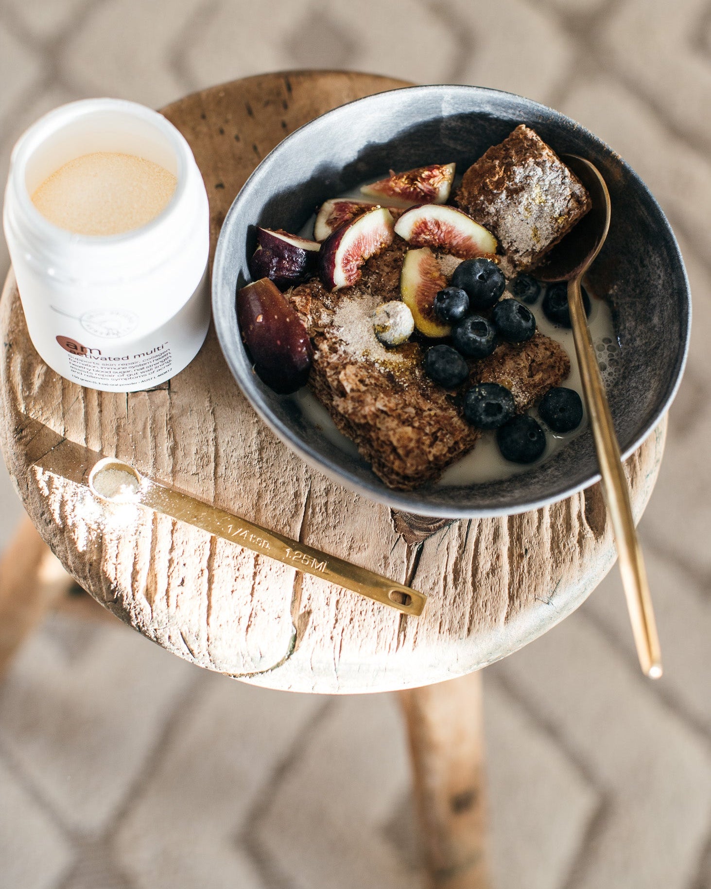 Breakfast scene with a bowl of cereal, fruit, and a cup of coffee on a wooden table.