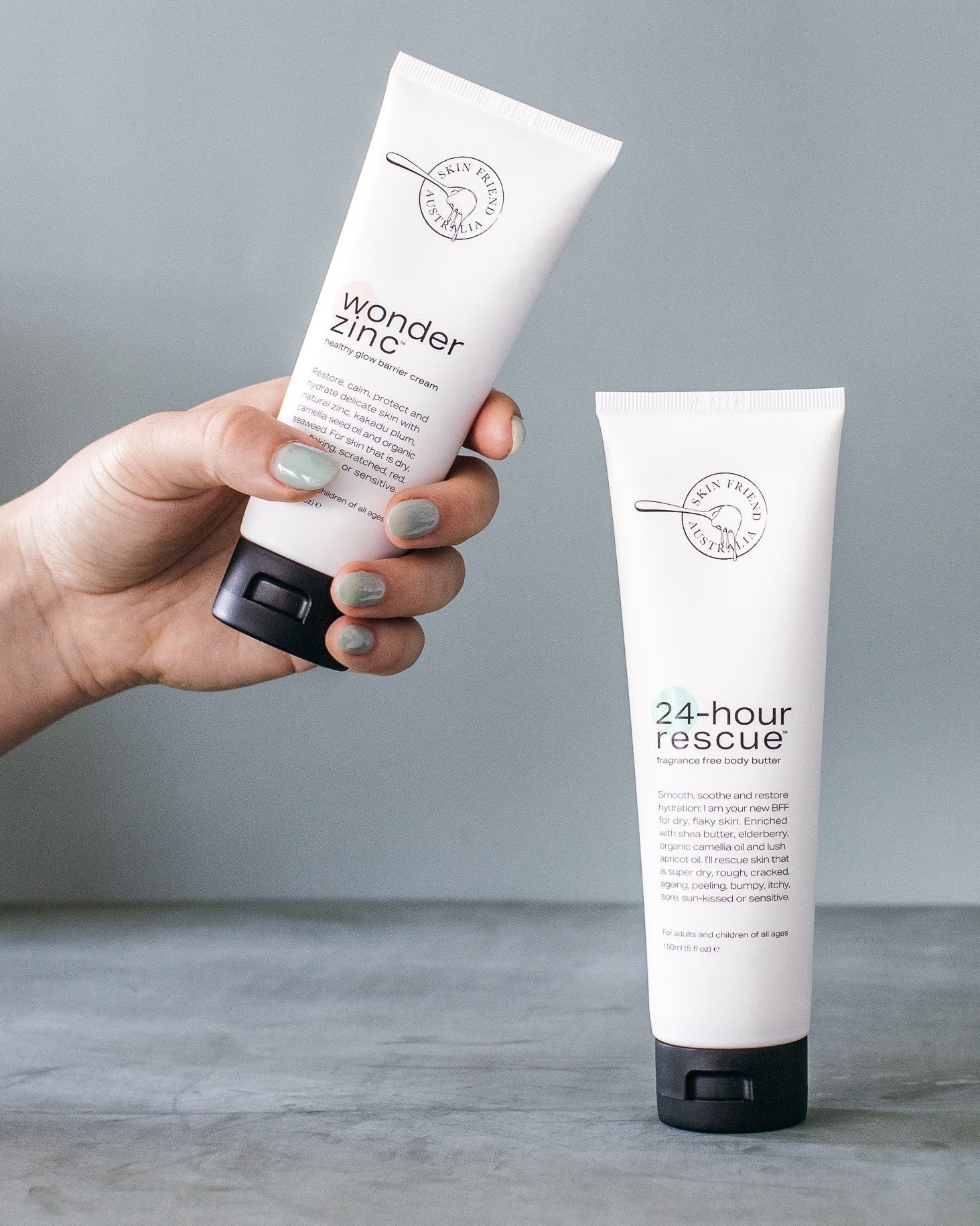 Hand holding a tube of 'wonder zinc' with another tube labeled '24-hour rescue' on a gray background