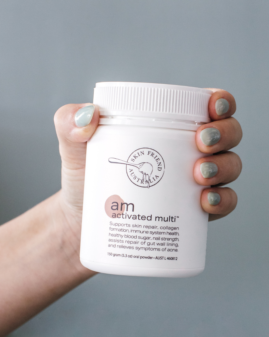 Hand holding a white container labeled 'am activated multi' against a gray background