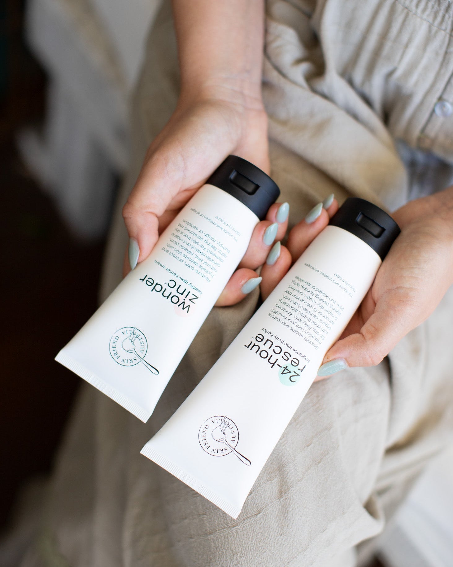 Two tubes of skincare, Wonder Zinc and 24-Hour Rescue, held by a person with light sage green nail polish.