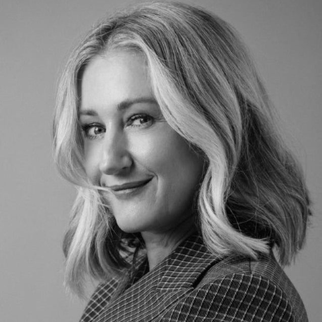 Black and white portrait of a woman with blonde hair wearing a checkered coat.
